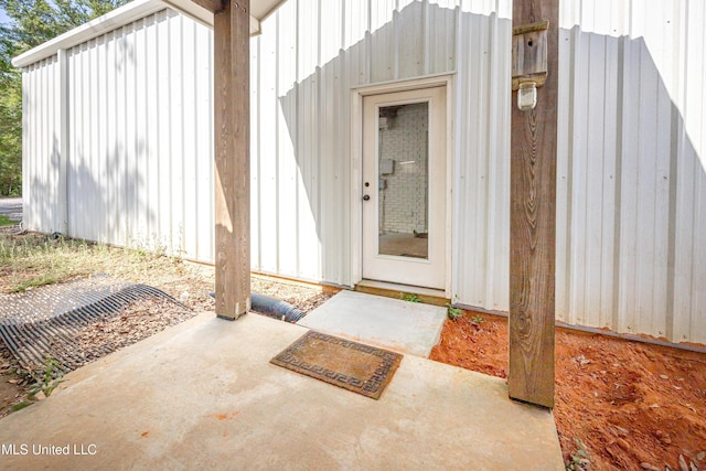 view of exterior entry with board and batten siding and a patio area