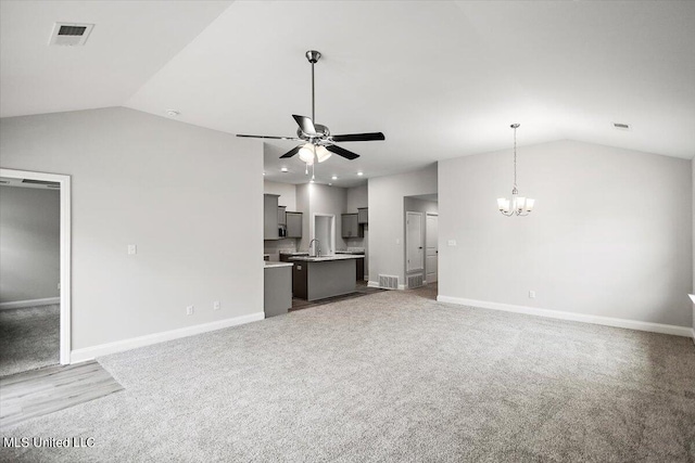 unfurnished living room featuring sink, light carpet, lofted ceiling, and ceiling fan with notable chandelier