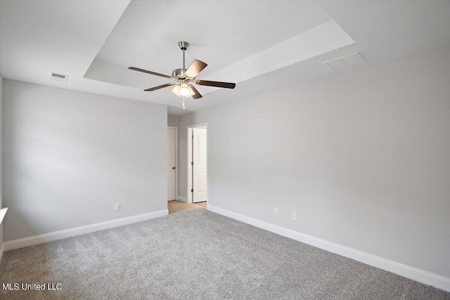 unfurnished room featuring light carpet, a tray ceiling, and ceiling fan