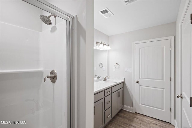 bathroom featuring hardwood / wood-style floors, vanity, and a shower