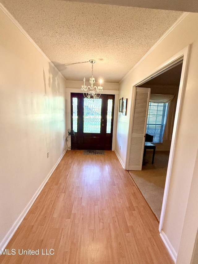 entryway with wood-type flooring, a textured ceiling, an inviting chandelier, and plenty of natural light