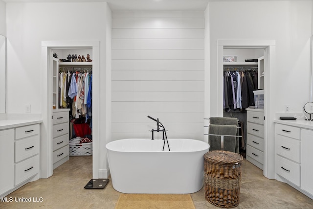 full bath with finished concrete floors, a freestanding tub, a spacious closet, and wooden walls