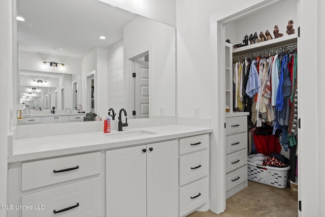 bathroom with recessed lighting, a spacious closet, and vanity