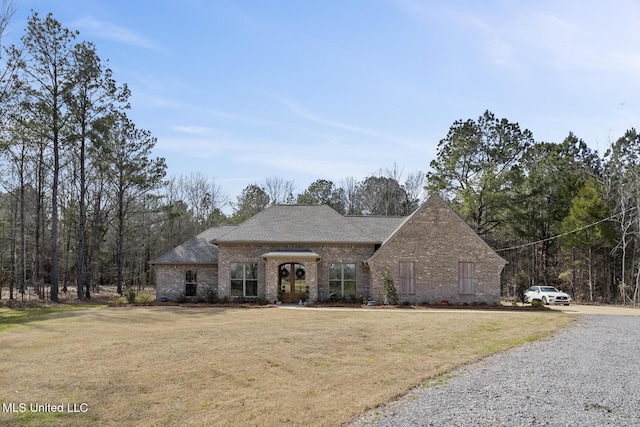 view of front of house with brick siding, roof with shingles, and a front yard