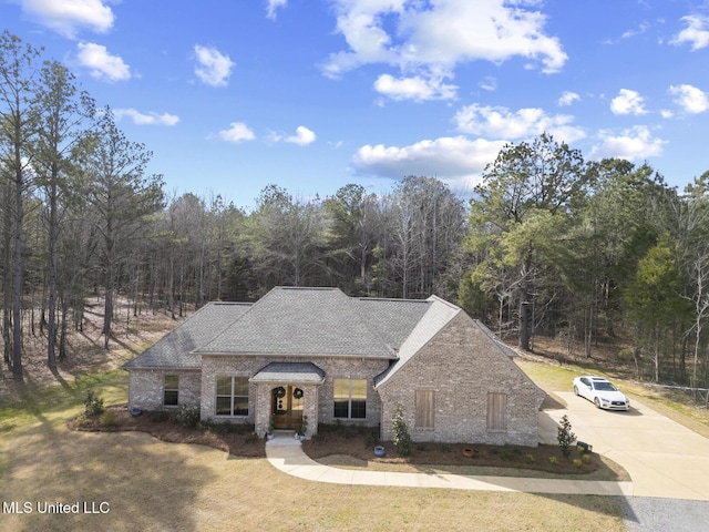 view of front facade with a shingled roof, concrete driveway, and brick siding