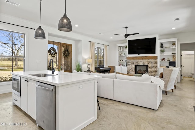 kitchen featuring stainless steel appliances, visible vents, a sink, and an island with sink