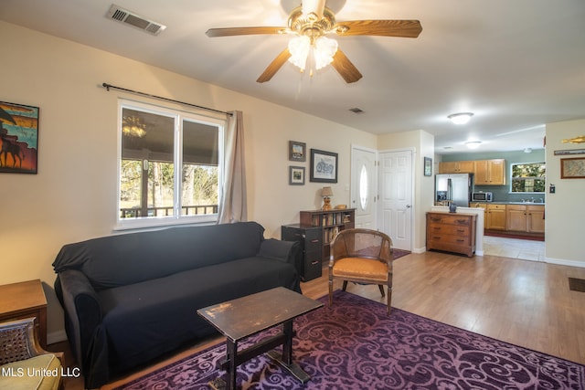 living room with sink, light hardwood / wood-style flooring, and ceiling fan