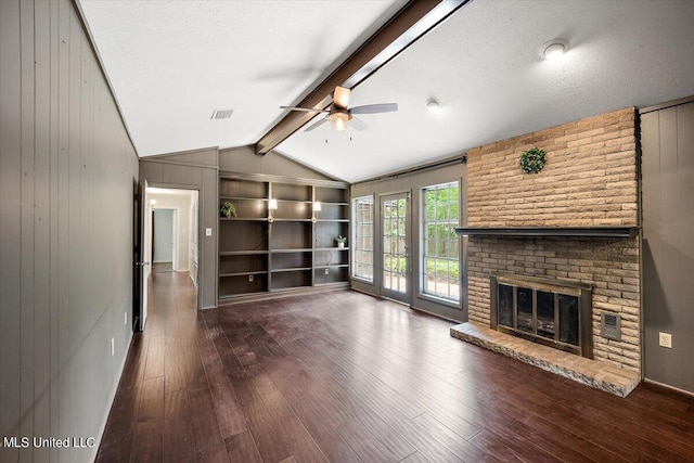 unfurnished living room with ceiling fan, a textured ceiling, a brick fireplace, dark wood-type flooring, and lofted ceiling with beams