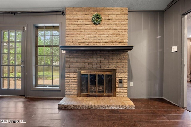 unfurnished living room featuring plenty of natural light, dark wood-type flooring, a fireplace, and crown molding