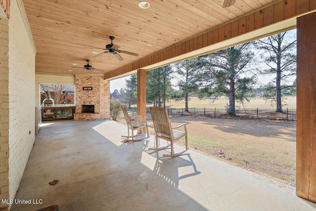 view of patio / terrace featuring an outdoor brick fireplace, a rural view, and ceiling fan