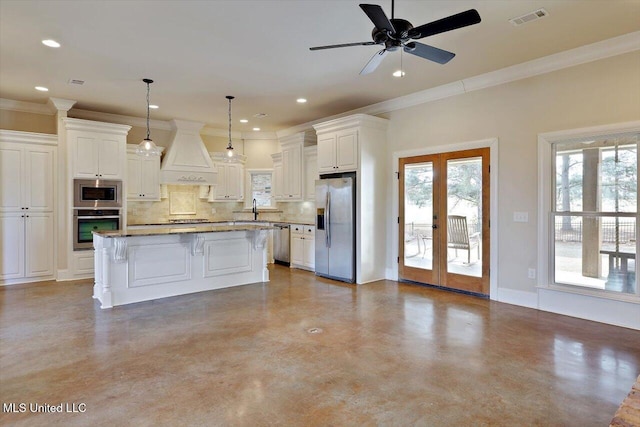 kitchen with custom exhaust hood, appliances with stainless steel finishes, a center island, and decorative light fixtures