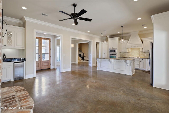 kitchen featuring premium range hood, a kitchen island, decorative light fixtures, white cabinetry, and wine cooler