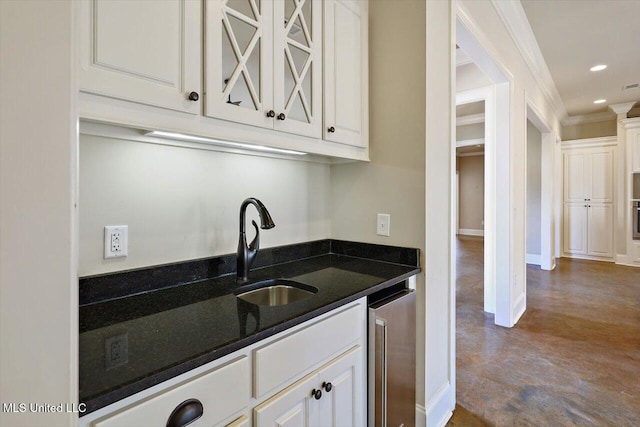 kitchen featuring sink, white cabinets, beverage cooler, dark stone counters, and crown molding