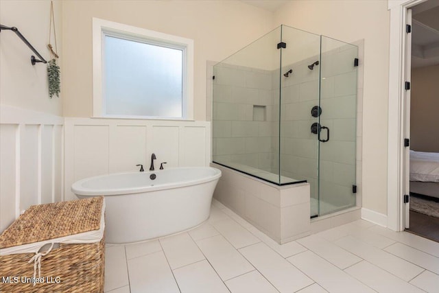 13604 Live Oak Loop, Olive Branch, MS 38654 - full bathroom featuring a shower stall, a freestanding tub, tile patterned flooring, a wainscoted wall, and a decorative wall