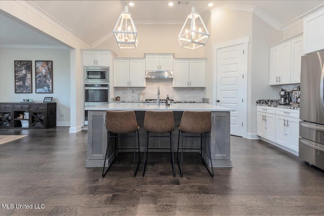 13604 Live Oak Loop, Olive Branch, MS 38654 - kitchen with stainless steel appliances, ornamental molding, under cabinet range hood, a kitchen island with sink, and vaulted ceiling