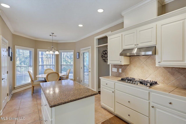 kitchen with white cabinets, a kitchen island, light tile patterned flooring, and stainless steel gas cooktop