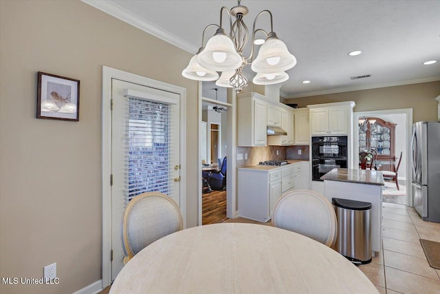 dining area with light tile patterned floors, ornamental molding, and a notable chandelier