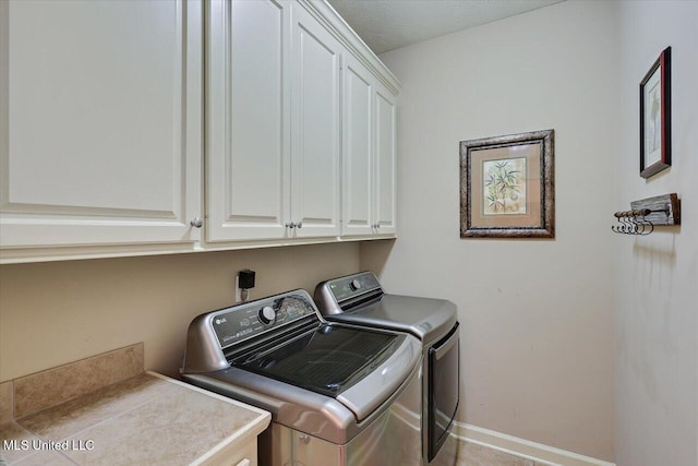 laundry room with washer and dryer, light tile patterned flooring, cabinets, and a textured ceiling