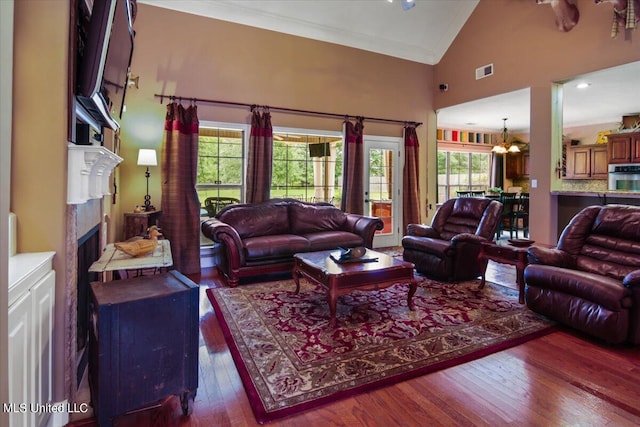 living room featuring a notable chandelier, a healthy amount of sunlight, high vaulted ceiling, and dark wood-type flooring