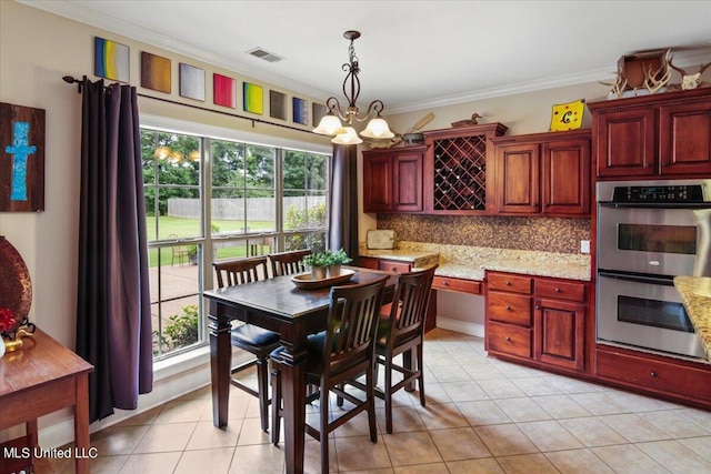 tiled dining area featuring ornamental molding and an inviting chandelier