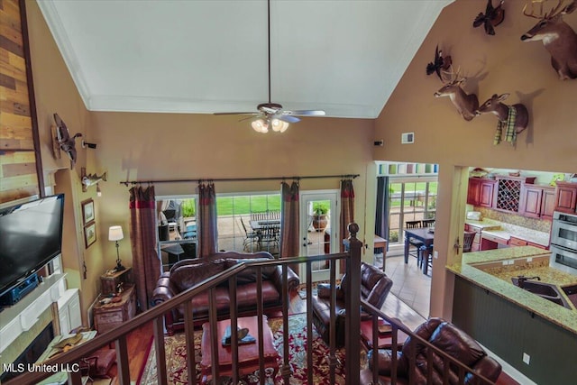 tiled living room featuring ornamental molding, ceiling fan, high vaulted ceiling, and a wealth of natural light