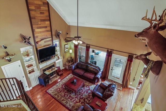 living room featuring hardwood / wood-style floors, crown molding, a towering ceiling, and ceiling fan