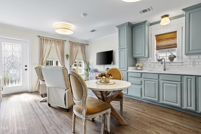 dining space featuring plenty of natural light, wood-type flooring, ornamental molding, and sink