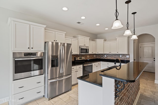 kitchen with arched walkways, stainless steel appliances, visible vents, white cabinetry, and a sink