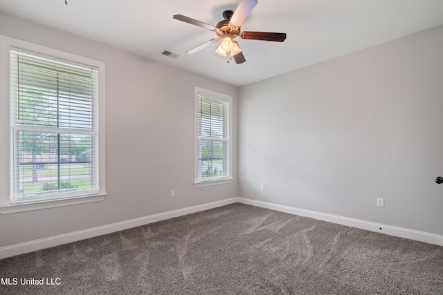 spare room featuring baseboards, visible vents, dark carpet, and ceiling fan