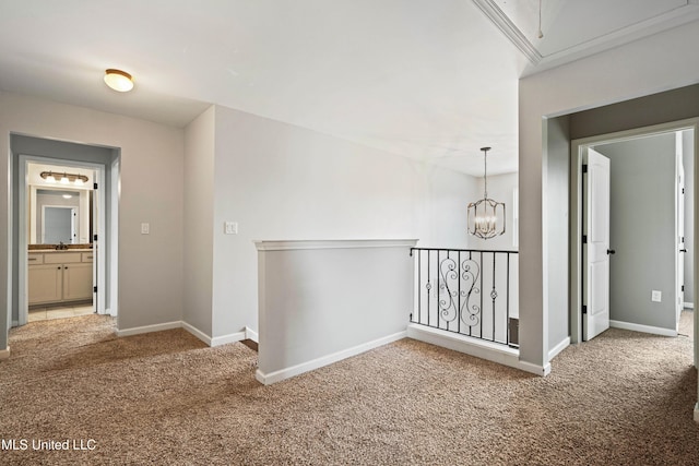 corridor featuring attic access, carpet, a notable chandelier, and baseboards