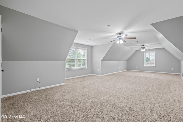 additional living space featuring plenty of natural light, baseboards, vaulted ceiling, and carpet flooring