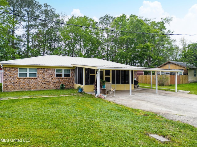 view of front of house with fence, metal roof, a sunroom, and a front lawn