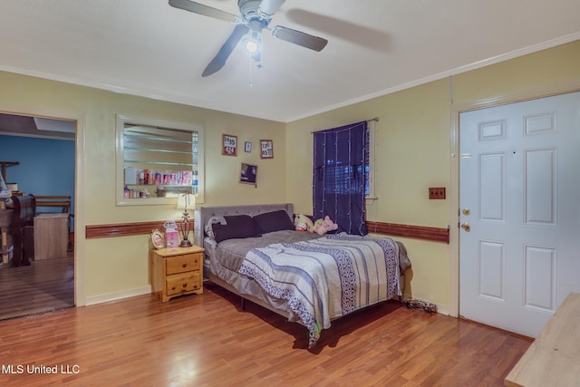 bedroom with baseboards, crown molding, a ceiling fan, and wood finished floors