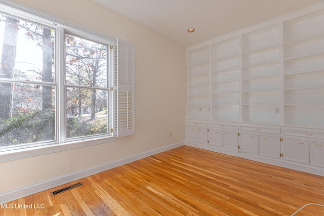 spare room with light hardwood / wood-style floors and built in features