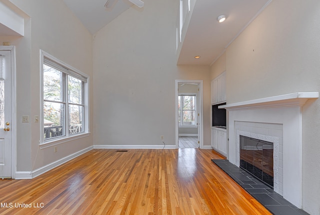 unfurnished living room featuring high vaulted ceiling, a fireplace, and hardwood / wood-style floors