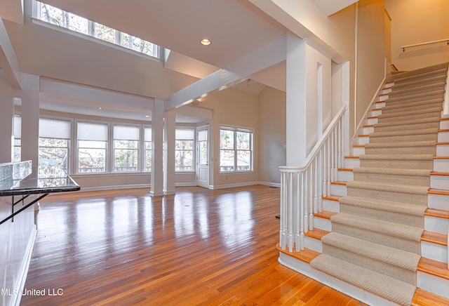 unfurnished living room featuring a towering ceiling, hardwood / wood-style floors, and decorative columns