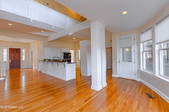 unfurnished living room with beam ceiling and light wood-type flooring