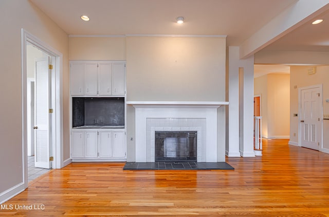 unfurnished living room featuring light hardwood / wood-style floors and a tile fireplace