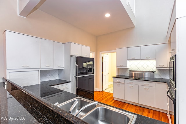 kitchen with tasteful backsplash, wood-type flooring, and black appliances