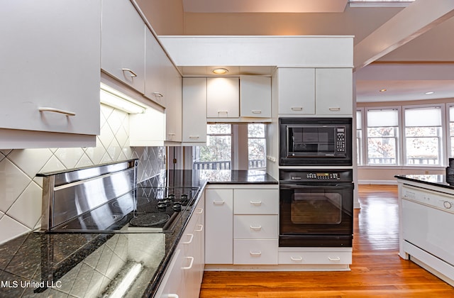 kitchen with light hardwood / wood-style floors, a healthy amount of sunlight, black appliances, and backsplash