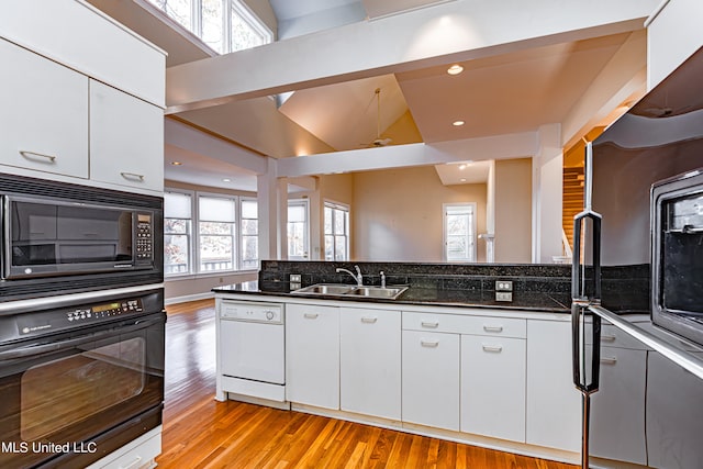 kitchen with sink, black appliances, white cabinetry, and dark stone countertops