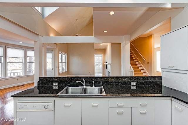 kitchen with dishwasher, dark stone counters, hardwood / wood-style floors, sink, and white cabinetry