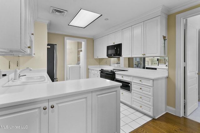 kitchen with a peninsula, visible vents, black appliances, and a sink
