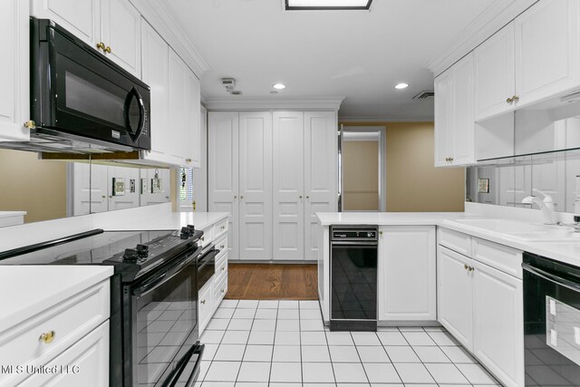 kitchen with kitchen peninsula, ornamental molding, sink, black appliances, and white cabinets