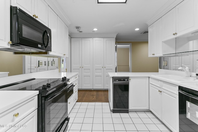 kitchen with a sink, ornamental molding, black appliances, visible vents, and white cabinetry