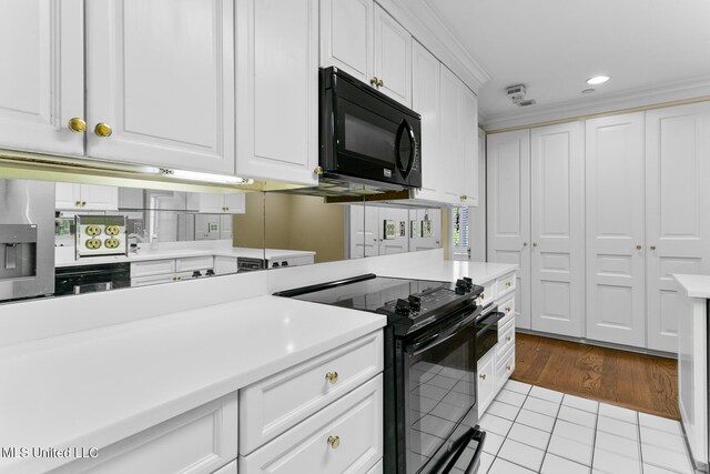 kitchen featuring ornamental molding, black appliances, light tile patterned floors, and white cabinets