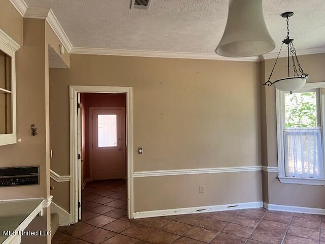 empty room featuring dark tile patterned floors, crown molding, and a textured ceiling