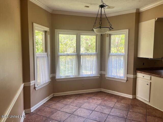 unfurnished dining area with ornamental molding and tile patterned flooring