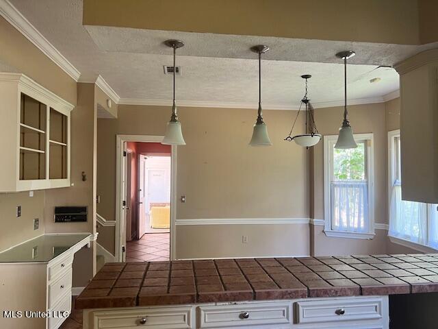 kitchen featuring white cabinetry, tile countertops, and decorative light fixtures