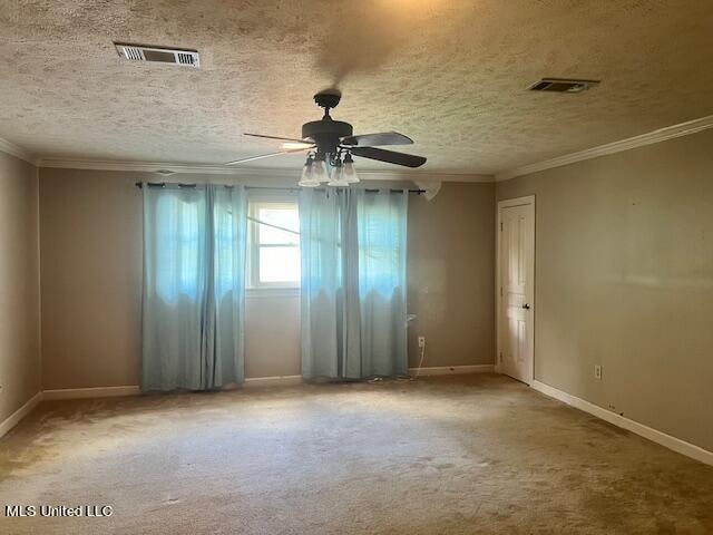 carpeted empty room featuring ceiling fan, crown molding, and a textured ceiling